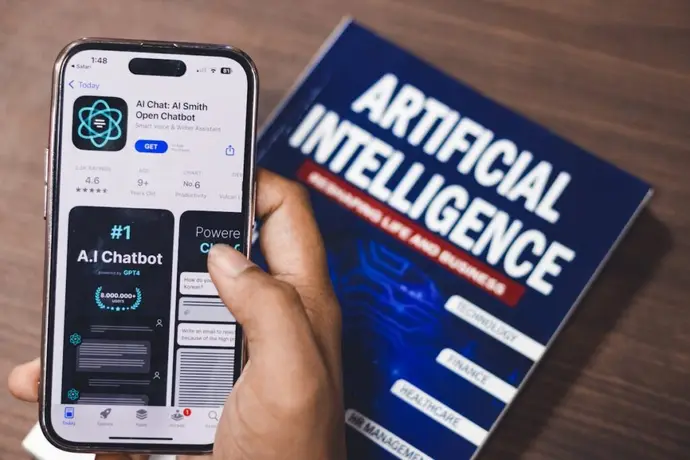 Smartphone displaying AI technology with a book on AI in the background