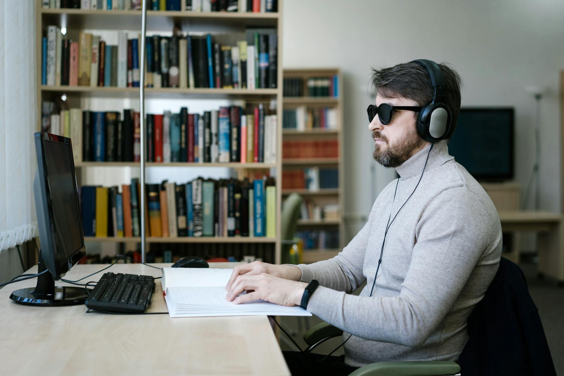 Blind man using braille reader and computer - web accessibility tools