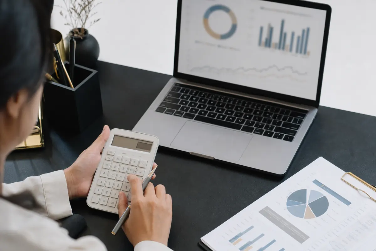 Marketing analyst using a calculator to compare ad spend and impressions