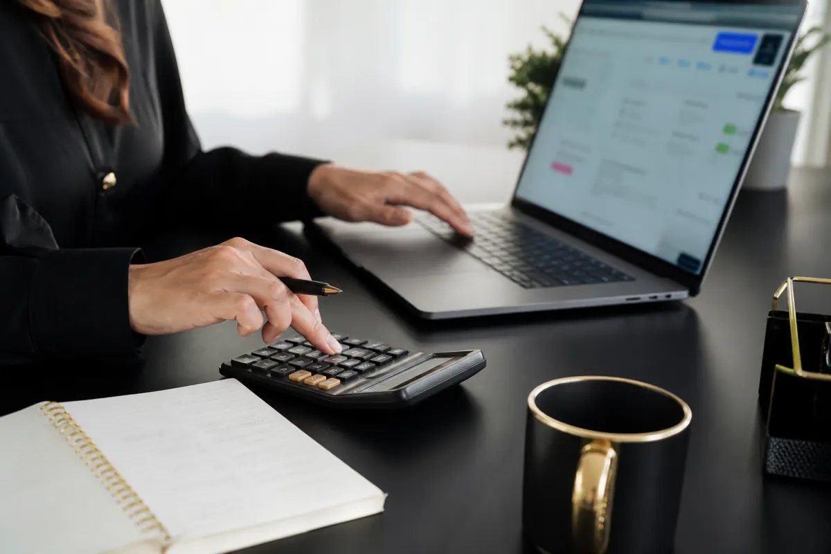 Marketer planning a monthly Google Ads budget with a laptop and calculator