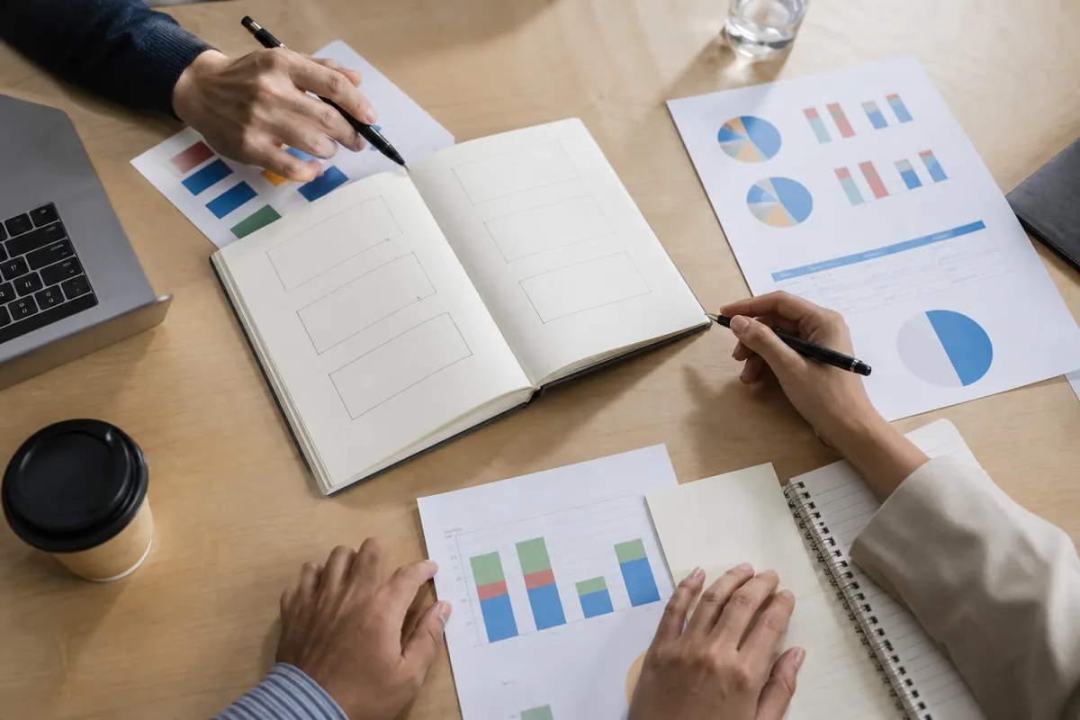 Marketing meeting agenda, notes, and performance materials arranged on a shared workspace
