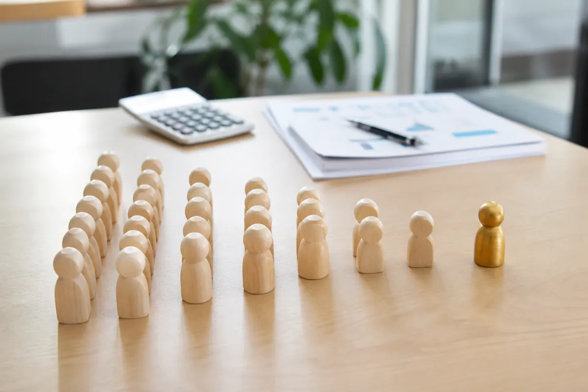 Wooden tokens arranged in narrowing rows to represent funnel forecasting
